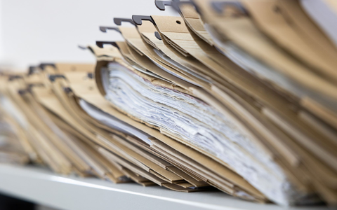Zahlreiche Akten sind auf einem Schreibtisch ausgelegt. - Foto: Lando Hass/dpa