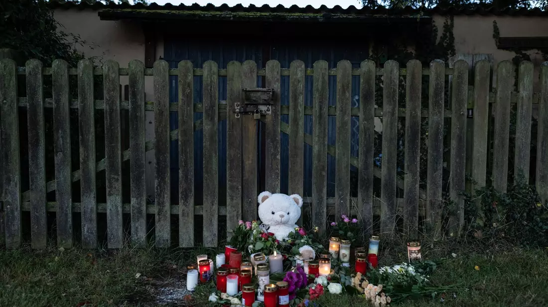 Menschen haben Kerzen, Blumen und ein Stofftier in Gedenken an die tote 14-Jährige vor einen Zaun gelegt. - Bild: Swen Pförtner/dpa