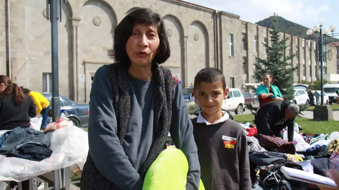 Margarita (l) und ihr Enkel Tigran sammeln nach der überstürzten Flucht aus Berg-Karabach Kleider. - Bild: André Ballin/dpa