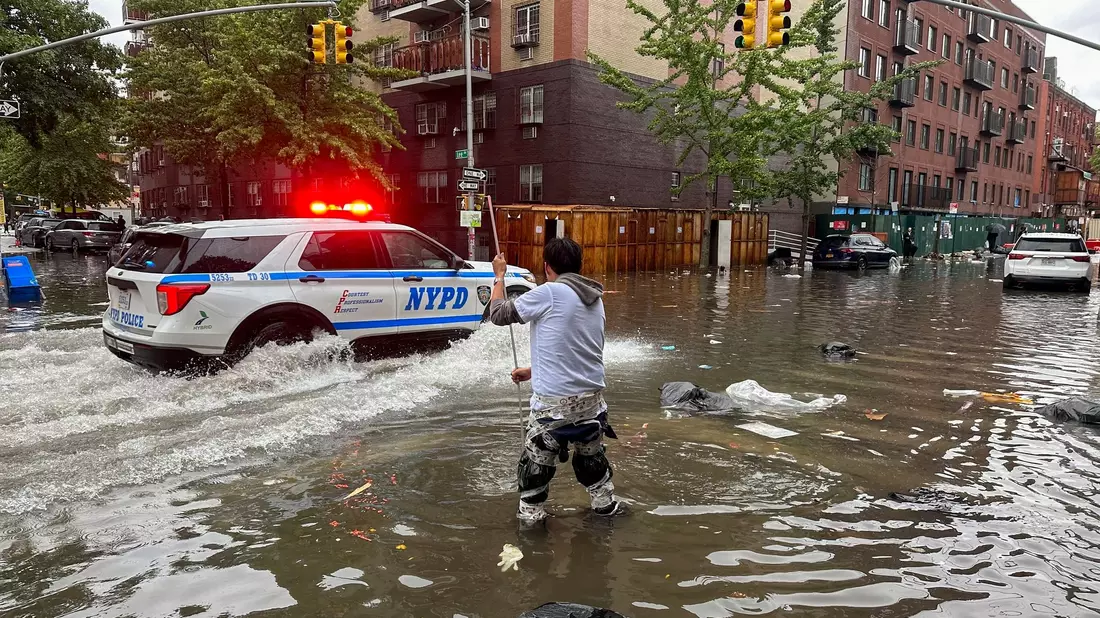 Ein Mann versucht im Stadtbezirk Brooklyn,  einen Abfluss im Hochwasser zu reinigen. Inzwischen ist das Wasser wieder versickert. - Bild: Jake Offenhartz/AP/dpa
