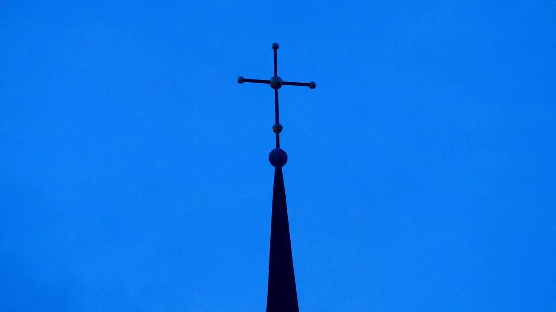 Kreuz einer evangelisch-lutherischen Kirche in der Abenddämmerung. - Bild: Friso Gentsch/dpa