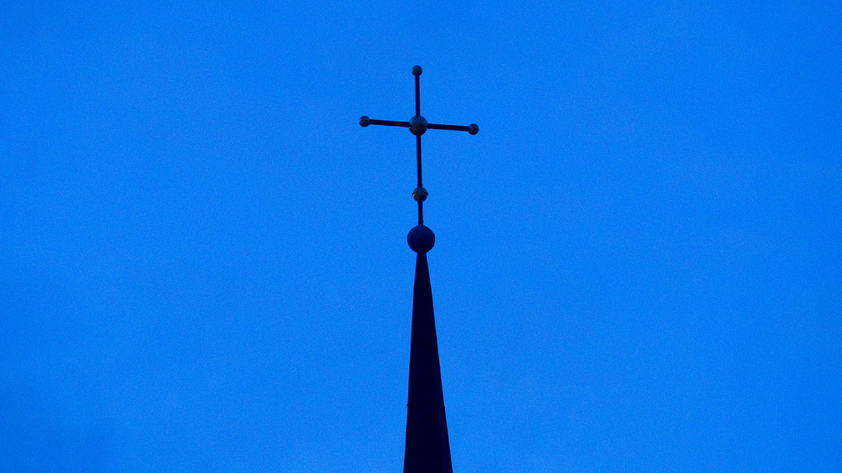 Kreuz einer evangelisch-lutherischen Kirche in der Abenddämmerung. - Foto: Friso Gentsch/dpa