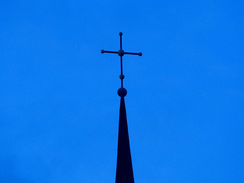 Kreuz einer evangelisch-lutherischen Kirche in der Abenddämmerung. - Foto: Friso Gentsch/dpa