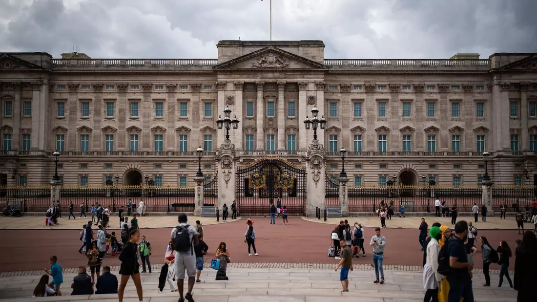 Touristen stehen vor den Toren vom Buckingham Palast in London. - Bild: Aaron Chown/PA Archive/dpa