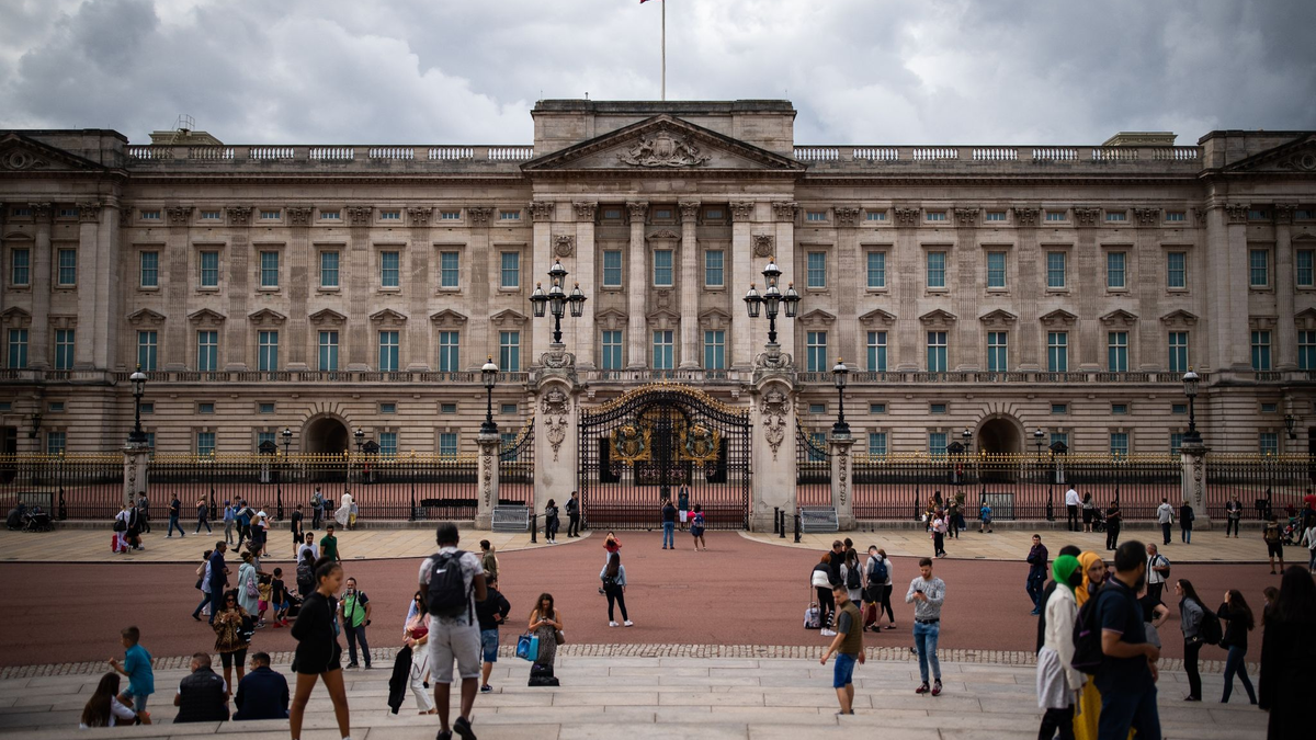 Touristen stehen vor den Toren vom Buckingham Palast in London. - Foto: Aaron Chown/PA Archive/dpa
