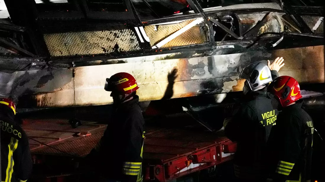 Feuerwehrleute arbeiten nach dem Busunglück an der Unfallstelle. - Bild: Antonio Calanni/AP