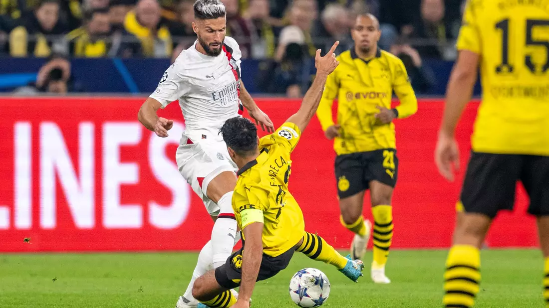BVB-Kapitän Emre Can versucht Milans Olivier Giroud (l.) den Ball abzugrätschen. - Bild: David Inderlied/dpa