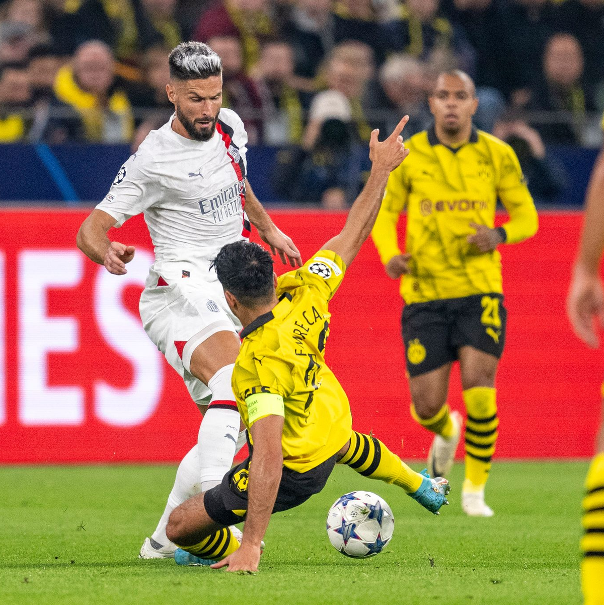 BVB-Kapitän Emre Can versucht Milans Olivier Giroud (l.) den Ball abzugrätschen. - Foto: David Inderlied/dpa