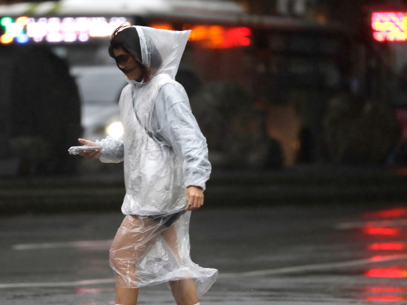 Eine Frau läuft bei Regen und Wind durch Taipeh. - Foto: ChiangYing-ying/AP/dpa