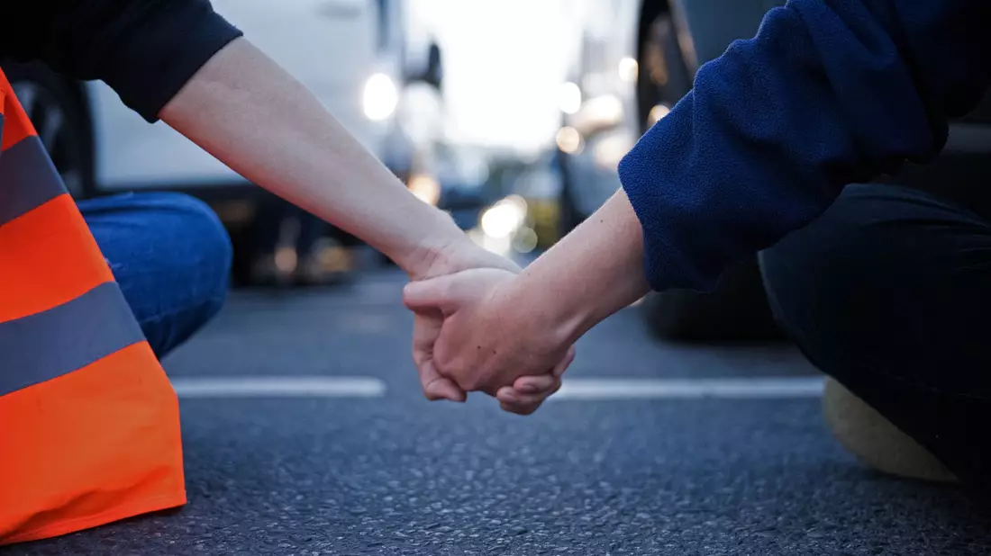 Aktivisten der Klimaschutzgruppe Letzte Generation halten sich während einer Straßenblockade an den Händen (Symbolbild). - Bild: Sebastian Christoph Gollnow/dpa