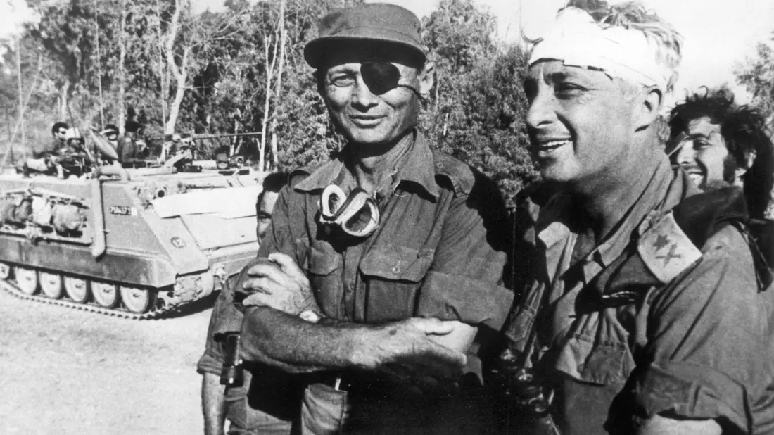 Der damalige israelische Verteidigungsminister und General Mosche Dajan (l.) mit dem damaligen Generalmajor Ariel Scharon, der einen Kopfverband trägt, aufgenommen im Oktober 1973 auf der ägyptischen Seite des Suezkanals während des 4. israelisch-arabischen Krieges. - Bild: UPI/dpa