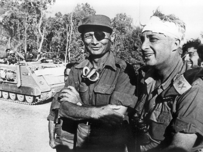Der damalige israelische Verteidigungsminister und General Mosche Dajan (l.) mit dem damaligen Generalmajor Ariel Scharon, der einen Kopfverband trägt, aufgenommen im Oktober 1973 auf der ägyptischen Seite des Suezkanals während des 4. israelisch-arabischen Krieges. - Foto: UPI/dpa