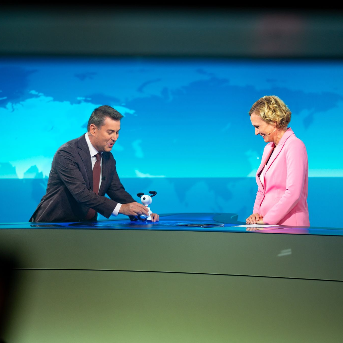 Jens Riewa (l-r) schenkt Caren Miosga am Ende ihrer letzten Sendung eine Snoopy-Figur. - Foto: Jonas Walzberg/dpa