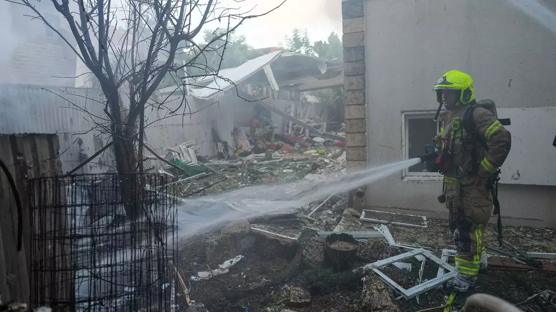 Israelische Feuerwehrleute löschen ein Feuer, nachdem eine aus dem Gazastreifen abgefeuerte Rakete ein Haus im Süden Israels getroffen hat. - Bild: Tsafrir Abayov/AP