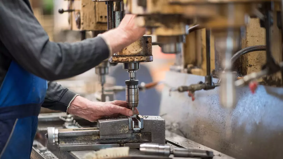 Ein Mitarbeiter bedient in einer Produktionshalle eine Maschine zur Verarbeitung von Metall. - Bild: Monika Skolimowska/zb/dpa