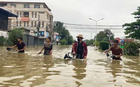 Anwohner schieben ihre Fahrräder durch eine überschwemmte Straße in Bago. - Foto: Thein Zaw/AP/dpa