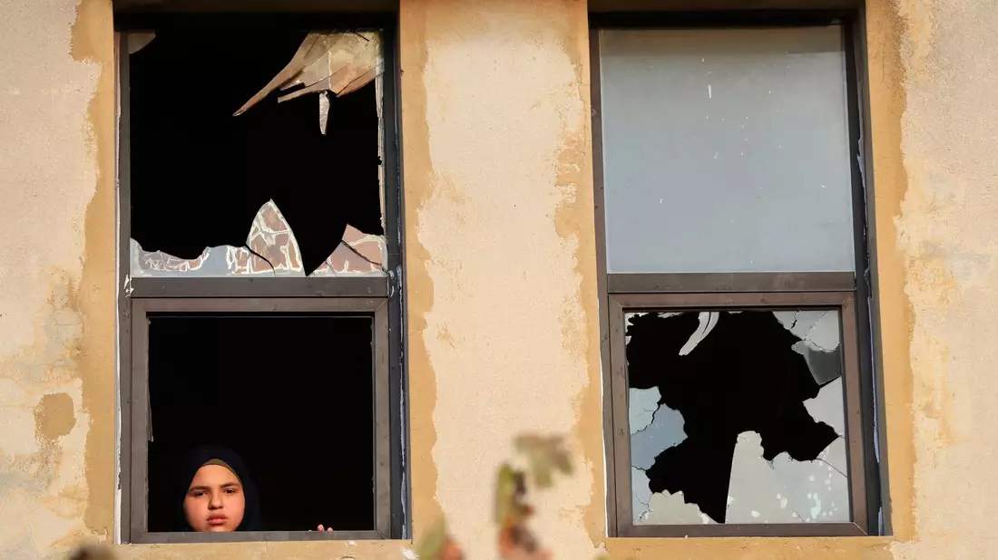 Ein libanesisches Mädchen blickt nach israelischem Beschuss auf ein Dorf im Südlibanon durch ein zerbrochenes Fenster. - Bild: Mohammed Zaatari/AP/dpa