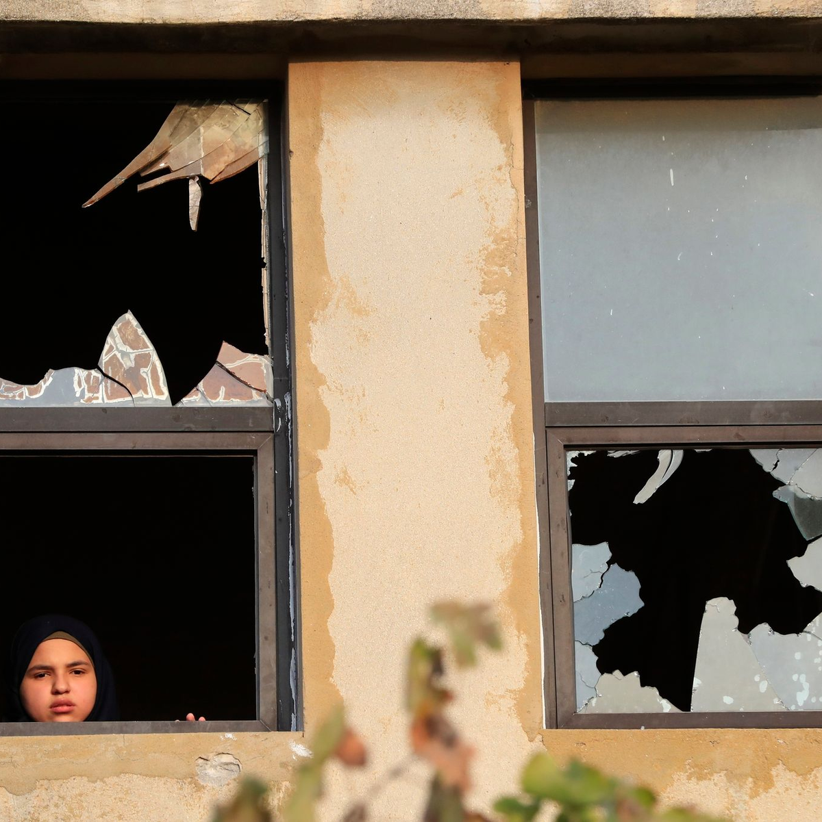 Ein libanesisches Mädchen blickt nach israelischem Beschuss auf ein Dorf im Südlibanon durch ein zerbrochenes Fenster. - Foto: Mohammed Zaatari/AP/dpa