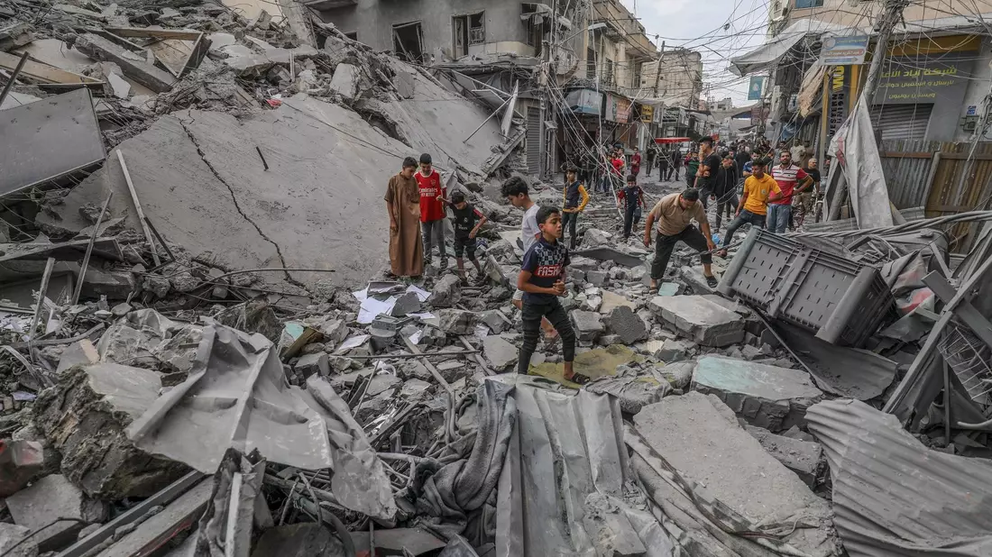 Palästinenser laufen nach einem israelischen Luftangriff im Gazastreifen zwischen den Trümmern eines zerstörten Gebäudes umher. - Bild: Abed Rahim Khatib/dpa