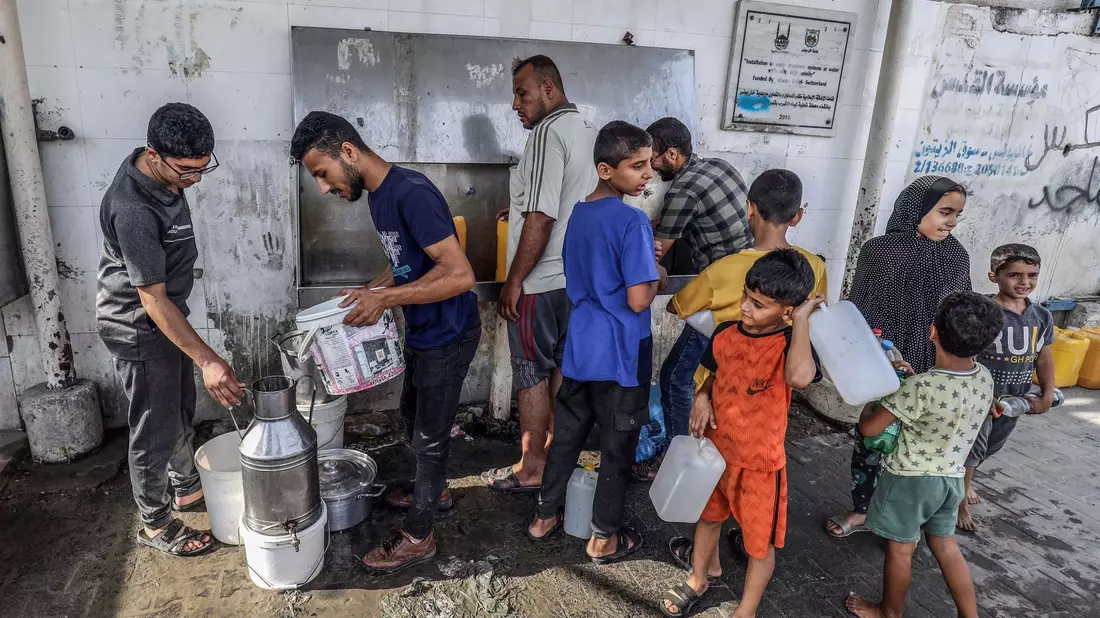 Palästinenser füllen an einem UN-Zentrum im Gazastreifen Flaschen mit Trinkwasser aus einem Wasserhahn. - Bild: Abed Rahim Khatib/dpa