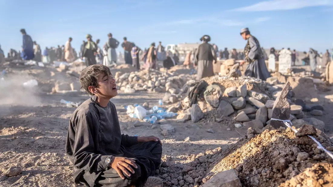 Ein Junge trauert neben dem Grab seines kleinen Bruders, der in der Provinz Herat im Westen Afghanistans ums Leben gekommen ist. - Bild: Ebrahim Noroozi/AP/dpa