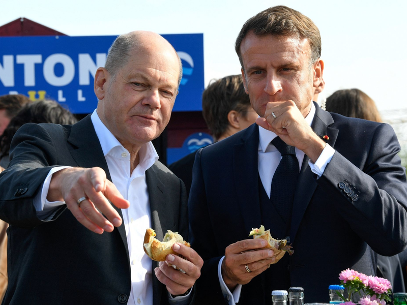 Bundeskanzler Olaf Scholz (SPD) und Frankreichs Präsident Emmanuel Macron (r) essen an der Elbe in Hamburg-Blankenese Fischbrötchen. - Foto: Fabian Bimmer/Reuters/Pool/dpa