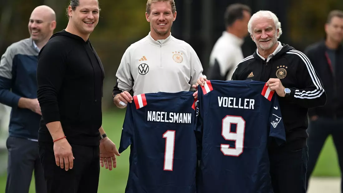 Julian Nagelsmann und Sportdirektor Rudi Völler mit Trikots der New England Patriots. - Bild: Federico Gambarini/dpa