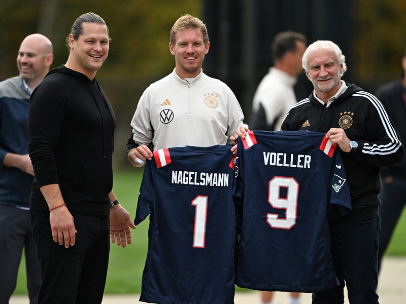 Julian Nagelsmann und Sportdirektor Rudi Völler mit Trikots der New England Patriots. - Foto: Federico Gambarini/dpa