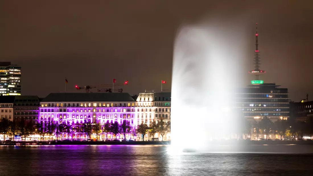 Das Hotel «Vier Jahreszeiten» an der Binnenalster in Hamburg ist während einer Aktion der Organisation «Plan International» zum Weltmädchentag beleuchtet. - Bild: Daniel Bockwoldt/dpa