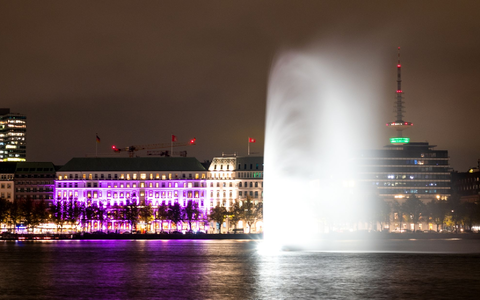 Das Hotel «Vier Jahreszeiten» an der Binnenalster in Hamburg ist während einer Aktion der Organisation «Plan International» zum Weltmädchentag beleuchtet. - Foto: Daniel Bockwoldt/dpa