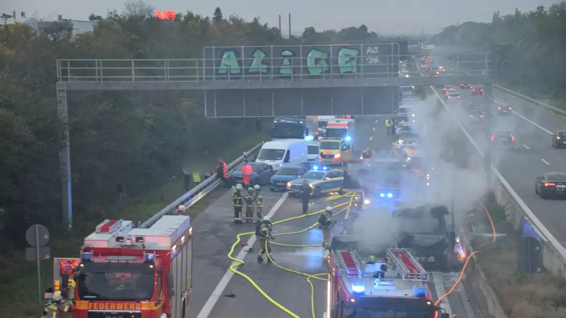Zahlreiche Einsatzkräfte der Feuerwehr bei Löscharbeiten an einem brennenden Fahrzeug auf der A5. - Bild: Rene Priebe/dpa