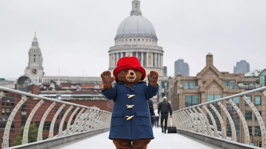 Ein Darsteller im Kostüm des Paddington-Bär  auf der Millenium-Brücke vor der Kuppel der St.-Pauls-Kathedrale in London. - Bild: Frank Augstein/AP/dpa