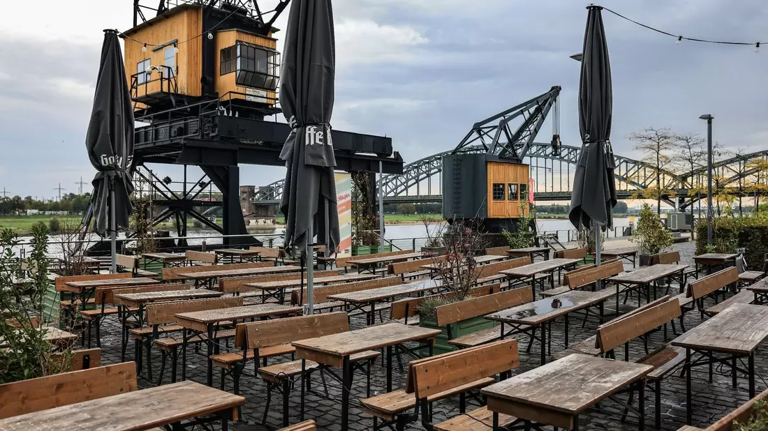 Leere Tische und Bänke am Rheinauhafen in Köln. - Bild: Oliver Berg/dpa