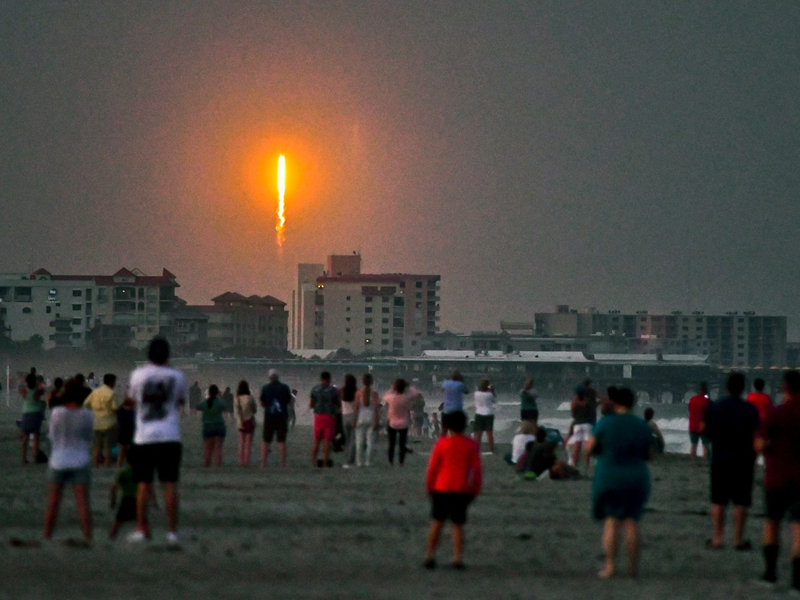 Menschen beobachten am Cocoa Beach im US-Bundesstaat Florida, wie die SpaceX-Rakete in Cape Canaveral abhebt. - Foto: Malcolm Denemark/Florida Today/AP/dpa