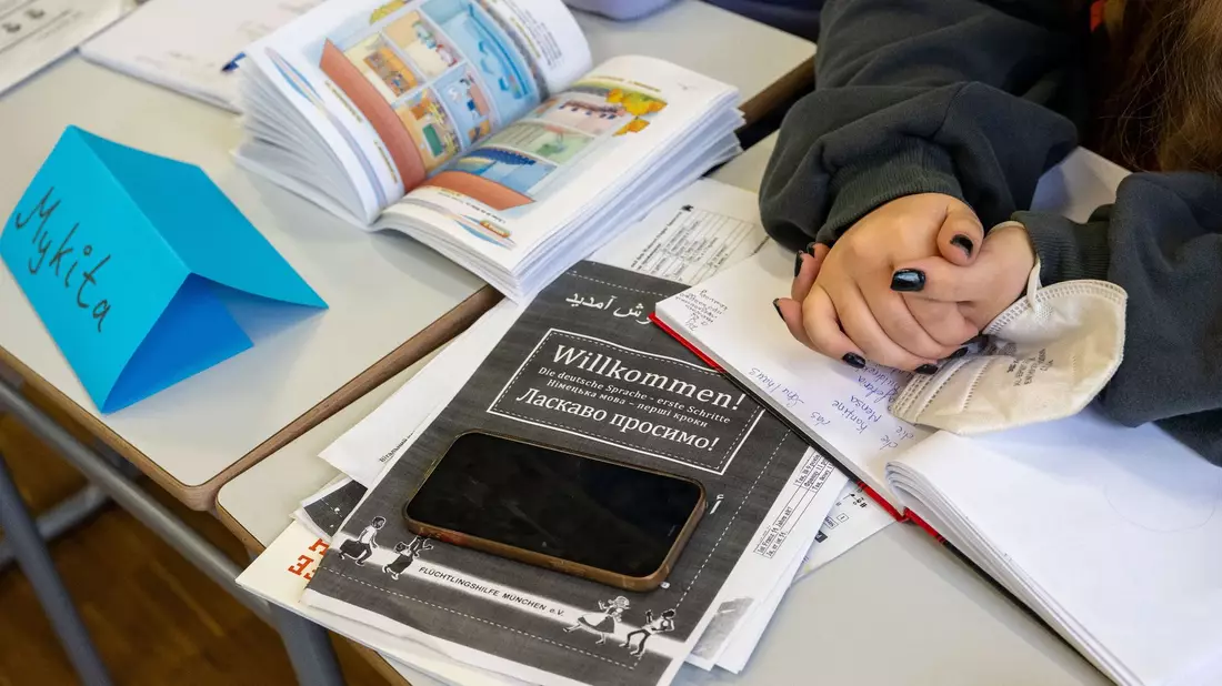 Ein Mädchen aus der Ukraine sitzt mit ihrem Unterrichtsmaterial in einer Klasse. - Bild: Peter Kneffel/dpa