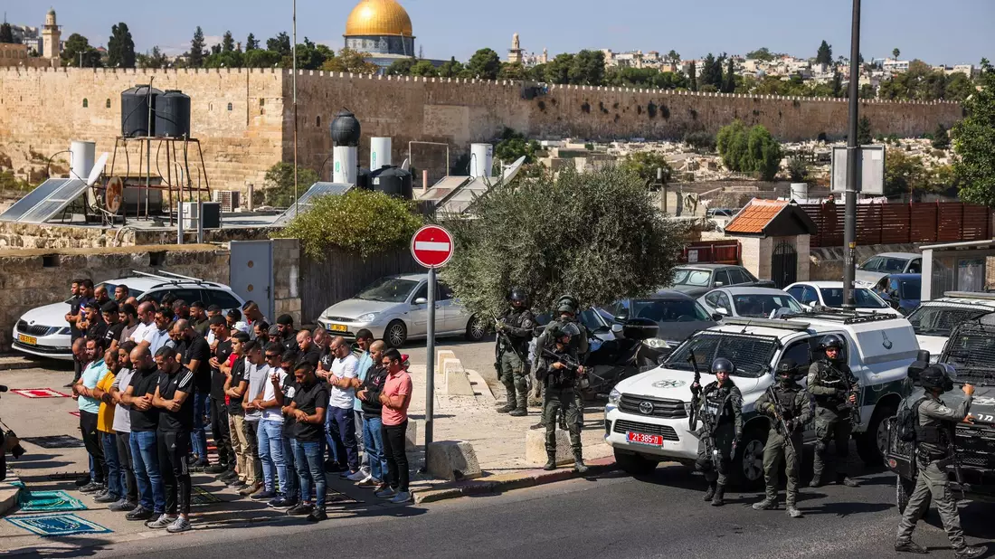 Palästinensische Gläubige beten außerhalb der Altstadt von Jerusalem, während israelische Streitkräfte Wache stehen. - Bild: Oren Ziv/dpa