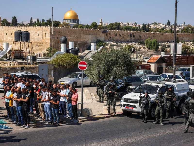 Palästinensische Gläubige beten außerhalb der Altstadt von Jerusalem, während israelische Streitkräfte Wache stehen. - Foto: Oren Ziv/dpa