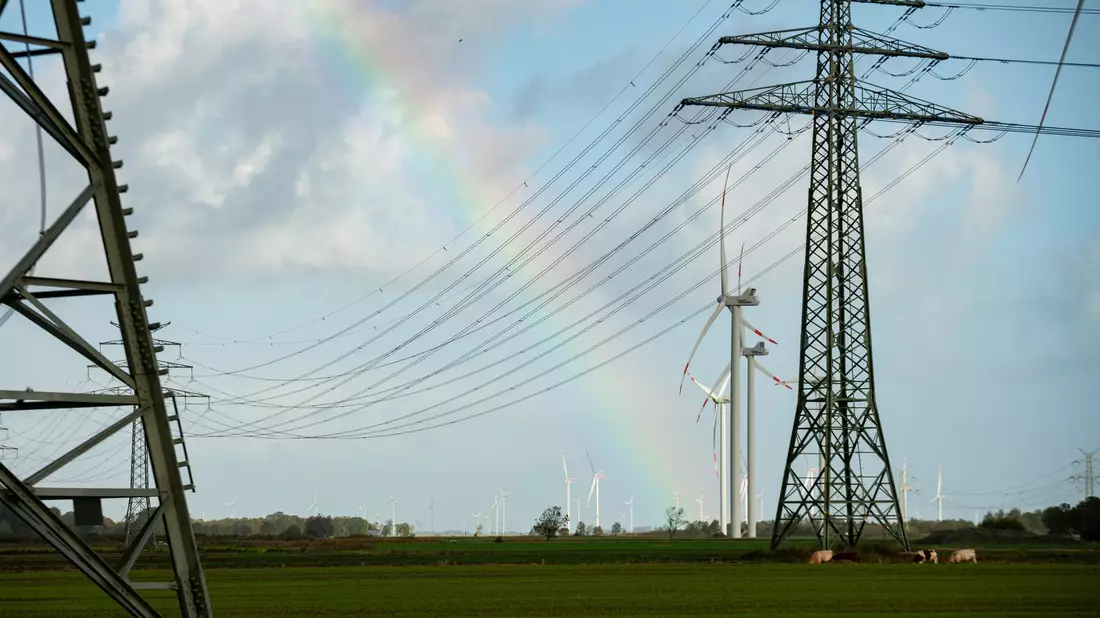 Ein Regenbogen zwischen Hochspannungsmasten und Windrädern in Schleswig-Holstein. Die für die Energiewende wichtige Westküstenleitung von der dänischen Grenze bis Brunsbüttel hat ihren Betrieb aufgenommen. - Bild: Jonas Walzberg/dpa