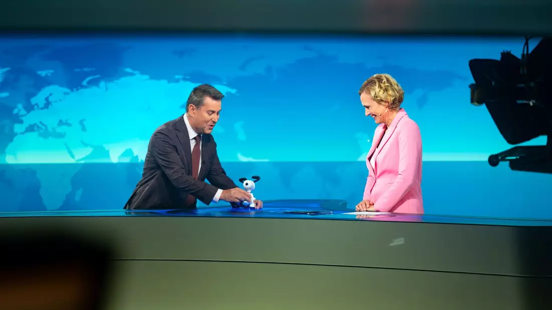 Jens Riewa (l-r) schenkt Caren Miosga am Ende ihrer letzten Sendung eine Snoopy-Figur. - Bild: Jonas Walzberg/dpa