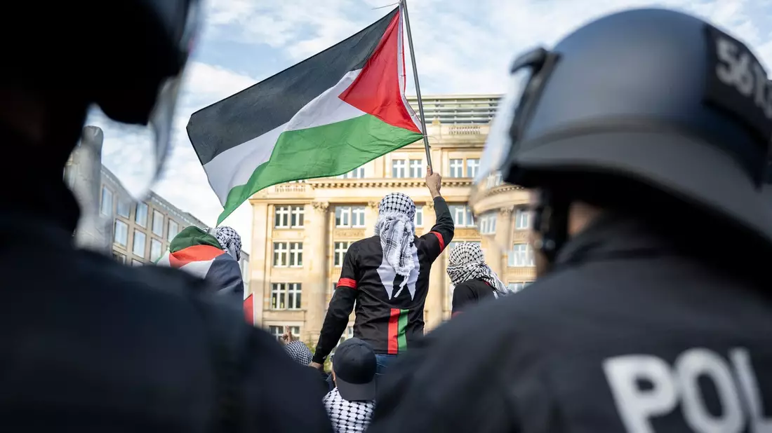 Ein Teilnehmer einer verbotenen Pro-Palästina-Demonstration in Frankfurt am Main schwenkt eine Palästina-Flagge, während Polizisten die Situation beobachten. - Bild: Hannes P. Albert/dpa