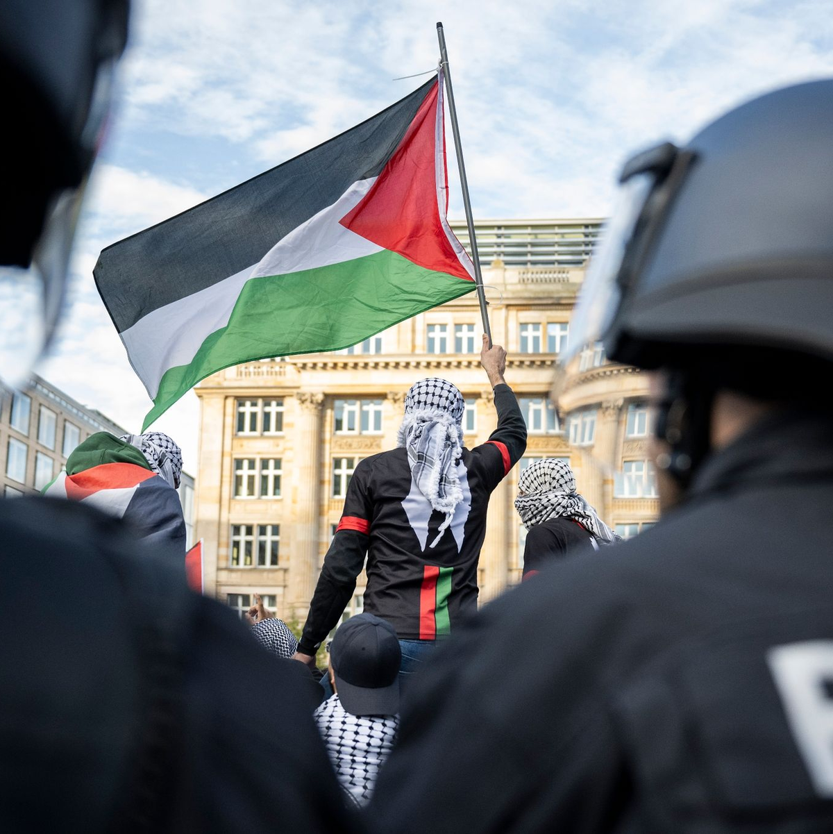 Ein Teilnehmer einer verbotenen Pro-Palästina-Demonstration in Frankfurt am Main schwenkt eine Palästina-Flagge, während Polizisten die Situation beobachten. - Foto: Hannes P. Albert/dpa