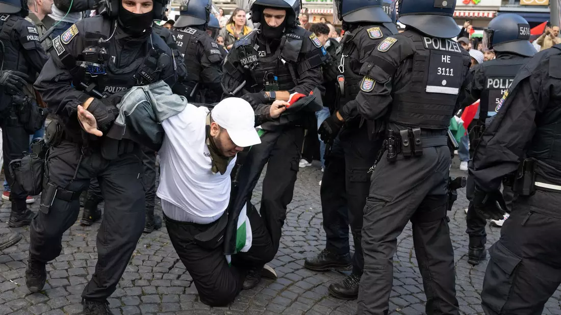 Polizisten halten am Rande der Pro-Palästina-Demo in Frankfurt am Main einen Teilnehmer fest. - Bild: Boris Roessler/dpa