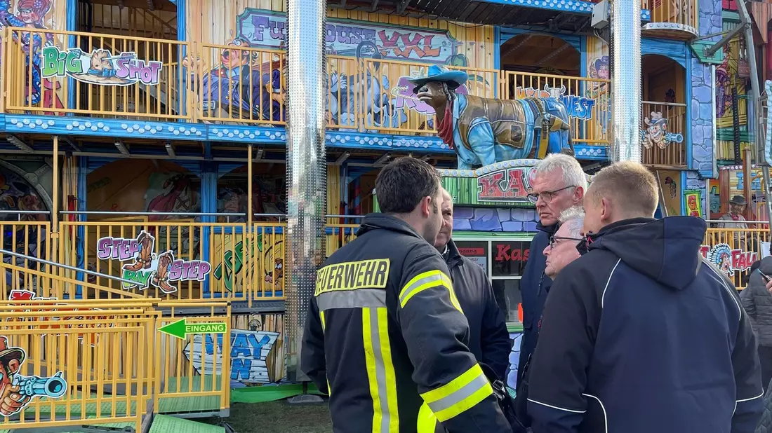 Feuerwehrleute und Polizisten stehen vor dem Funhouse auf dem Pollhansmarkt in Schloß Holte-Stukenbrock. - Bild: Christian Müller/Westfalennews/dpa
