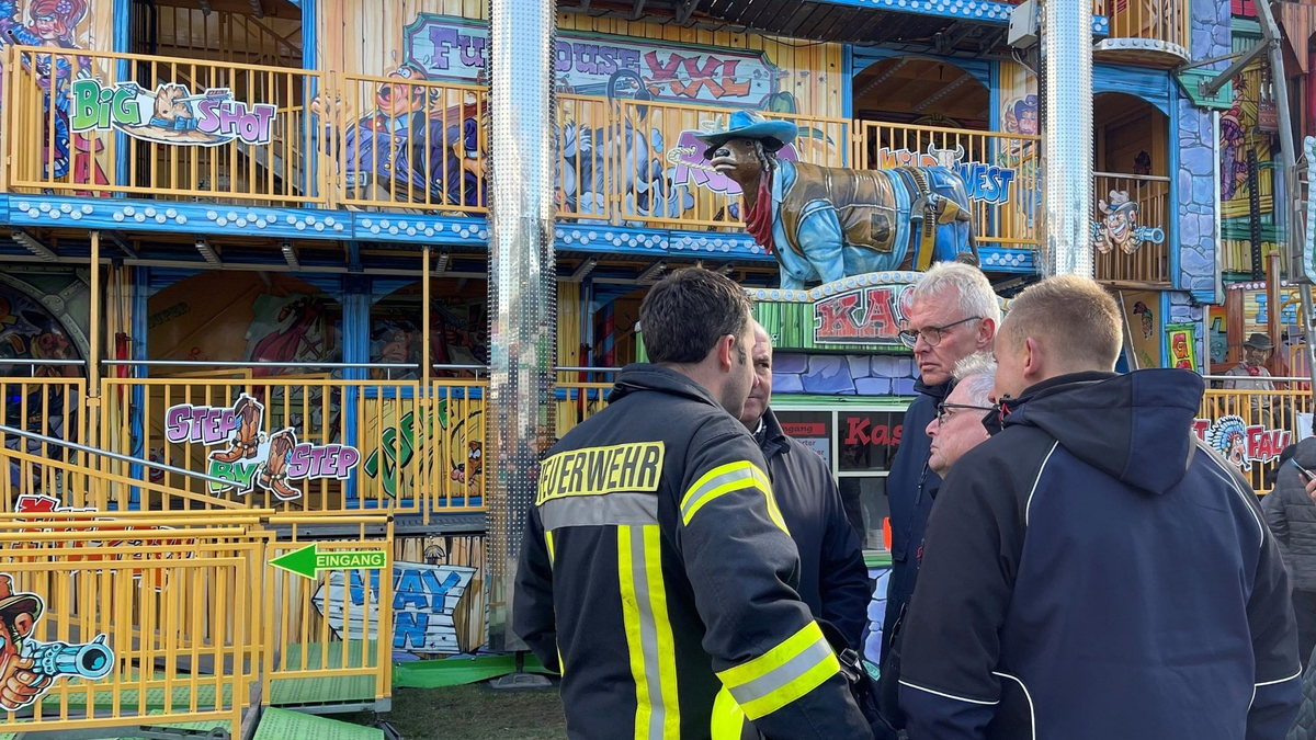 Feuerwehrleute und Polizisten stehen vor dem Funhouse auf dem Pollhansmarkt in Schloß Holte-Stukenbrock. - Foto: Christian Müller/Westfalennews/dpa