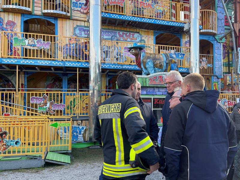 Feuerwehrleute und Polizisten stehen vor dem Funhouse auf dem Pollhansmarkt in Schloß Holte-Stukenbrock. - Foto: Christian Müller/Westfalennews/dpa