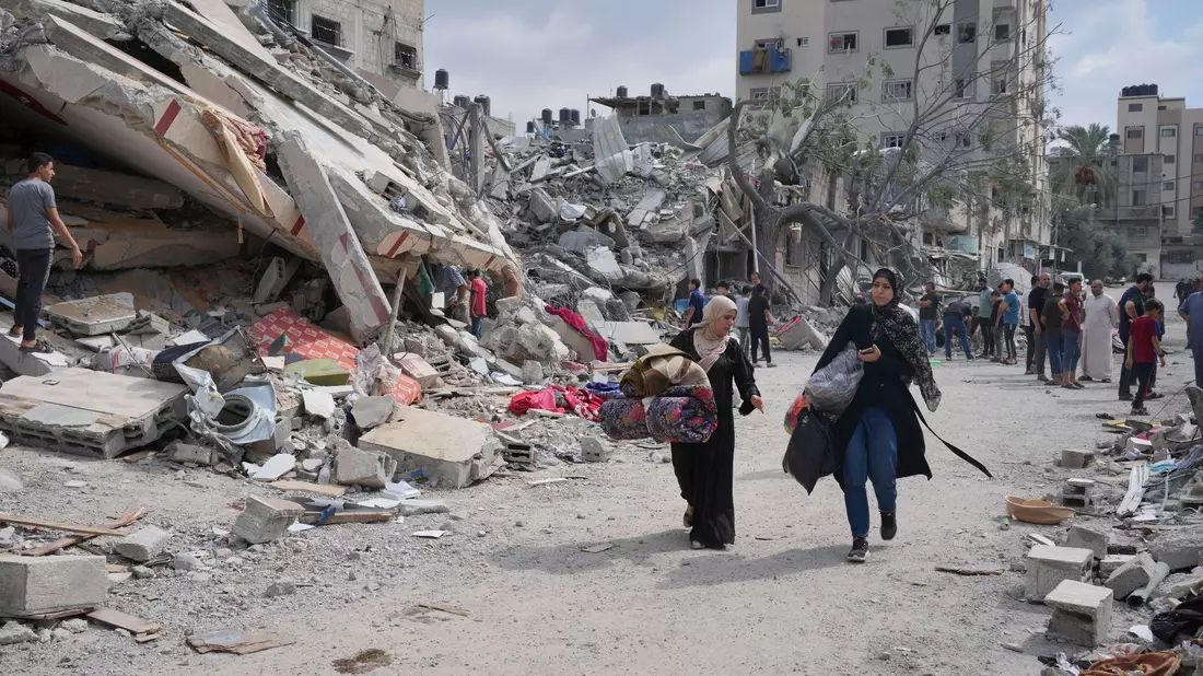 Palästinensische Frauen gehen in Nuseirat im Gazastreifen an Gebäuden vorbei, die bei israelischen Luftangriffen zerstört wurden. - Bild: Hatem Moussa/AP/dpa