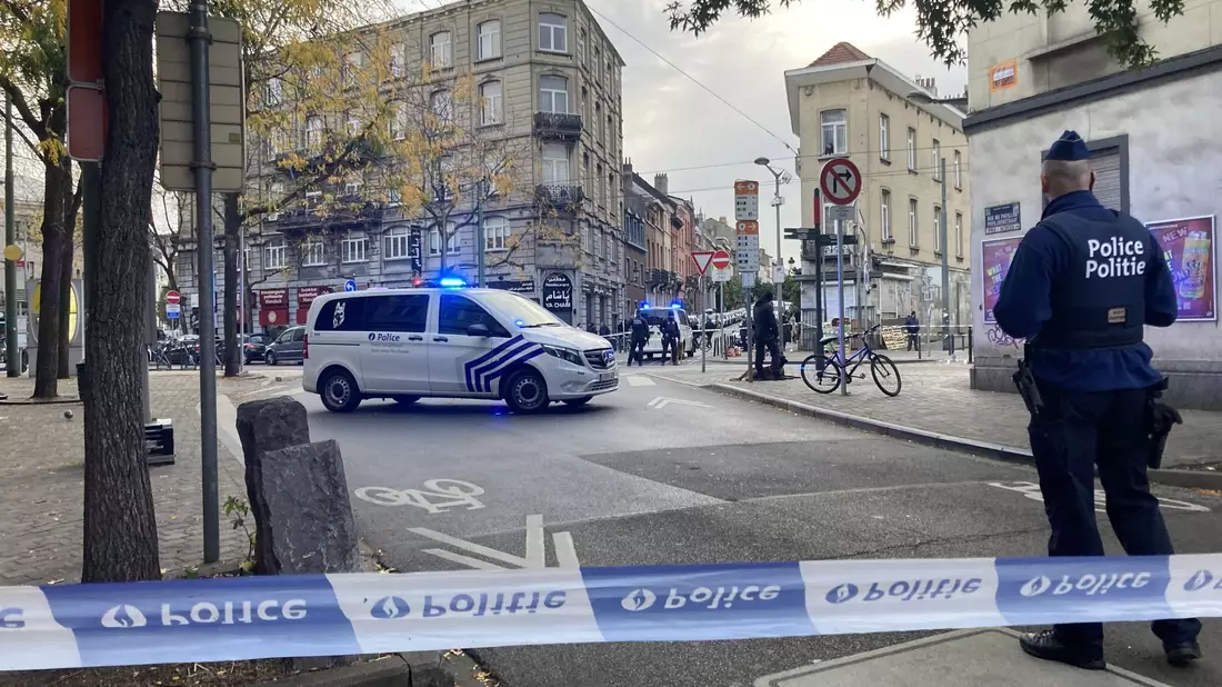 Die Polizei sperrt eine Straße, während ein Polizist hinter Absperrband Wache steht. - Bild: Lou Lampaert/Belga/dpa