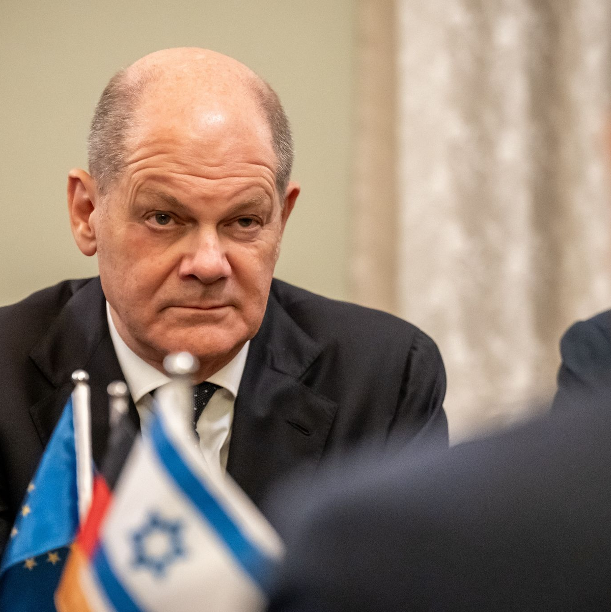 Bodyguards bringen Bundeskanzler Olaf Scholz (SPD, M) nach einem Luftalarm am Ende seines Solidaritätsbesuches in Israel in sein Flugzeug. - Foto: Michael Kappeler/dpa Pool/dpa