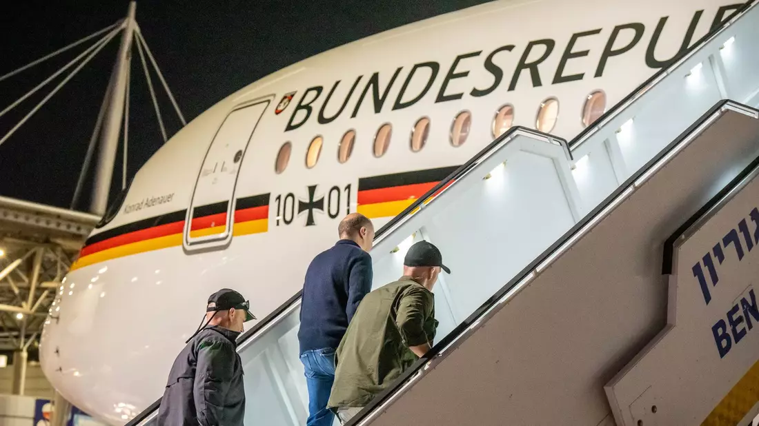 Bodyguards bringen Bundeskanzler Olaf Scholz nach dem Luftalarm in den Regierungs-Airbus. - Bild: Michael Kappeler/dpa Pool/dpa