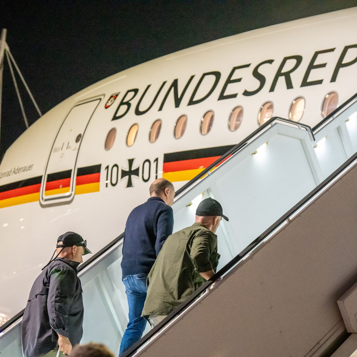 Bodyguards bringen Bundeskanzler Olaf Scholz nach dem Luftalarm in den Regierungs-Airbus. - Foto: Michael Kappeler/dpa Pool/dpa